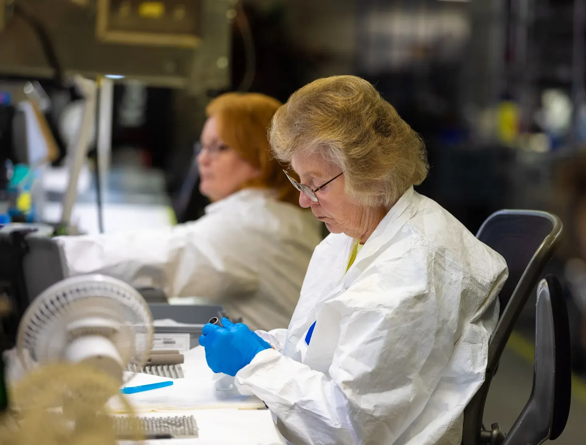 Technicians preparing medical device components in a controlled area