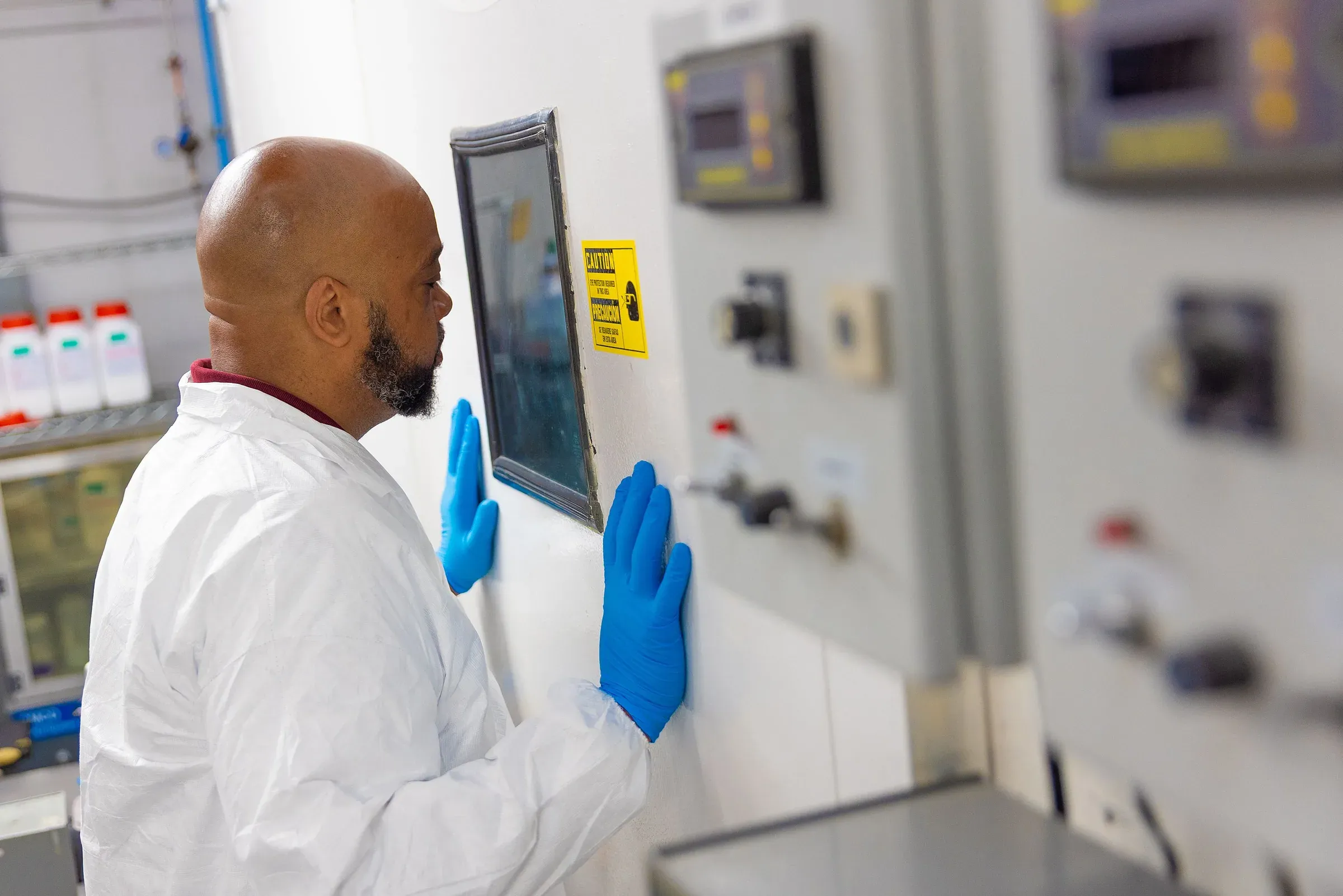 An APS Materials technician watching a spray run inside the cell
