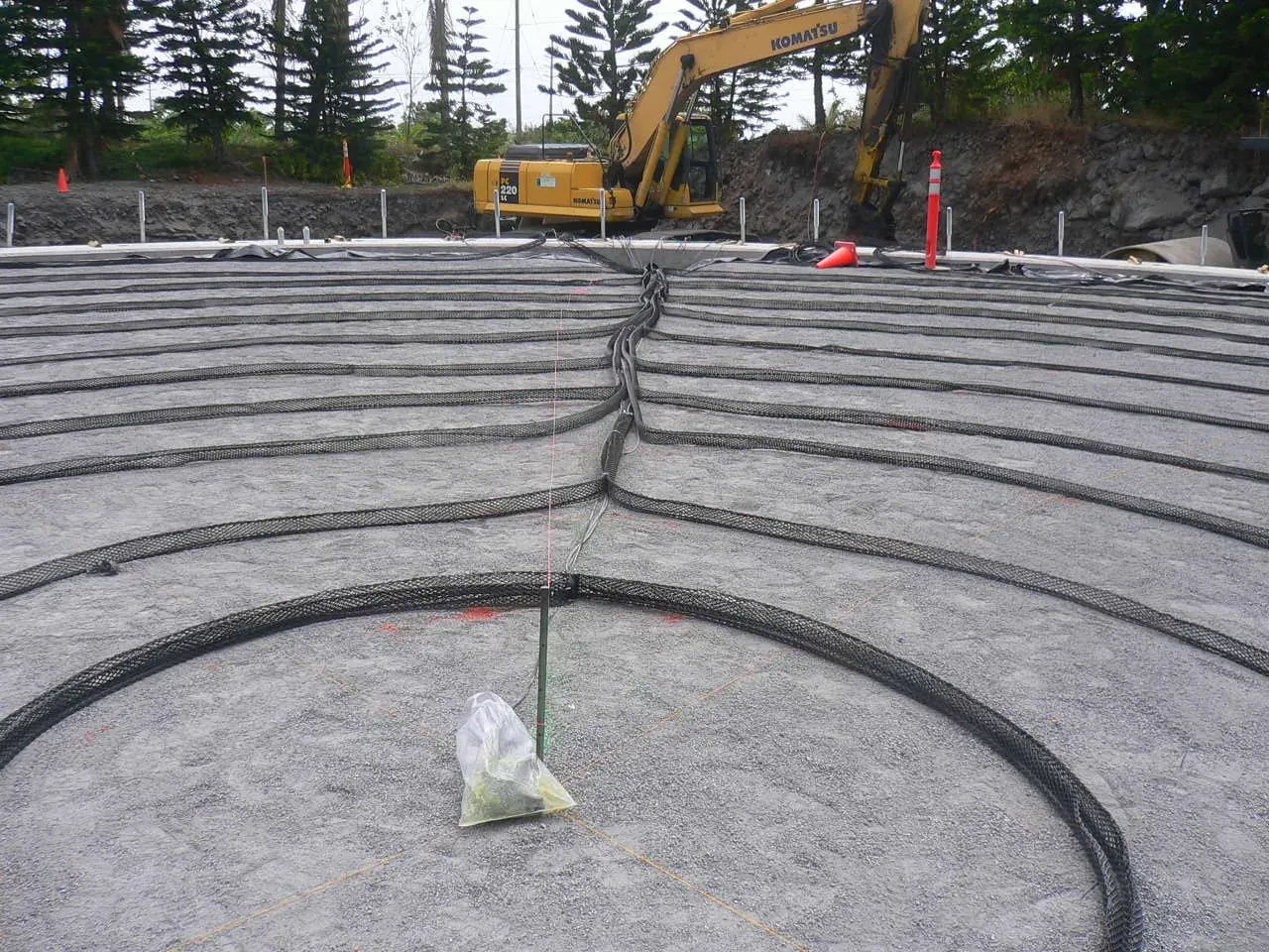 Piggyback tank bottom anode cable laid in rings across a prepared tank base