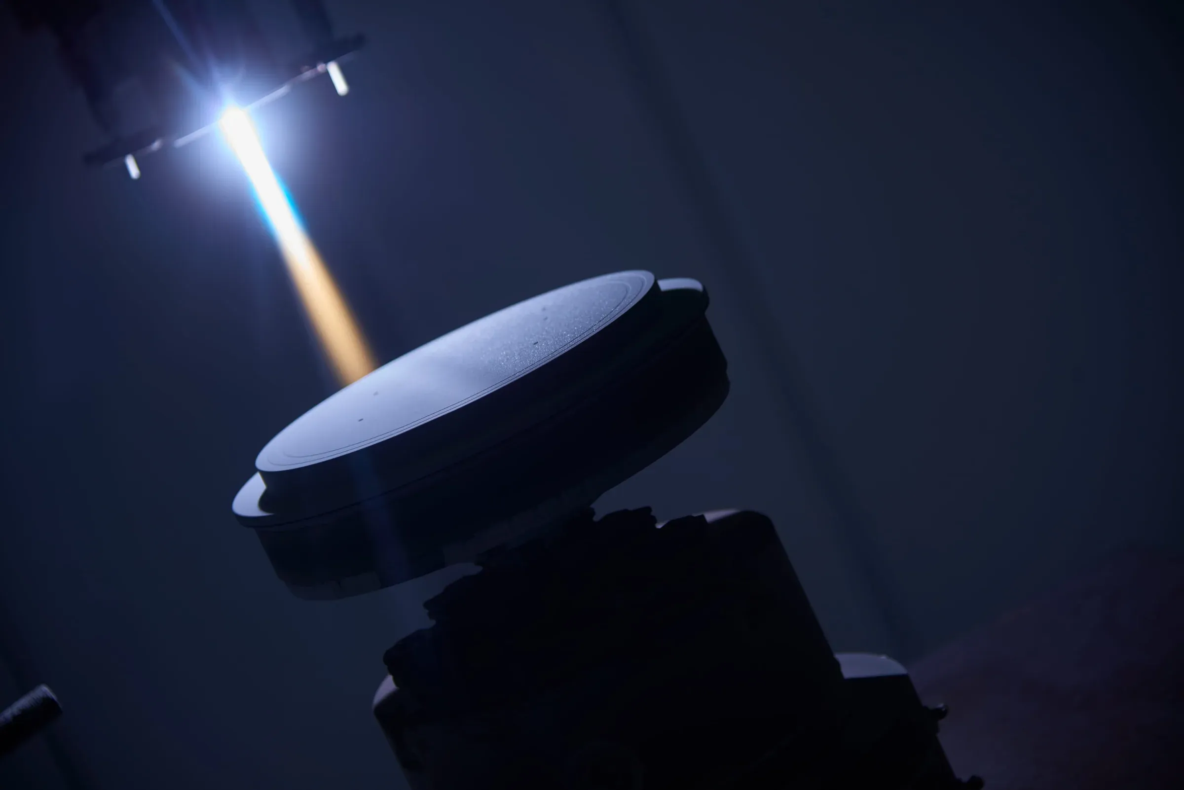 Plasma spray plume depositing a coating onto a disc-shaped electronics component