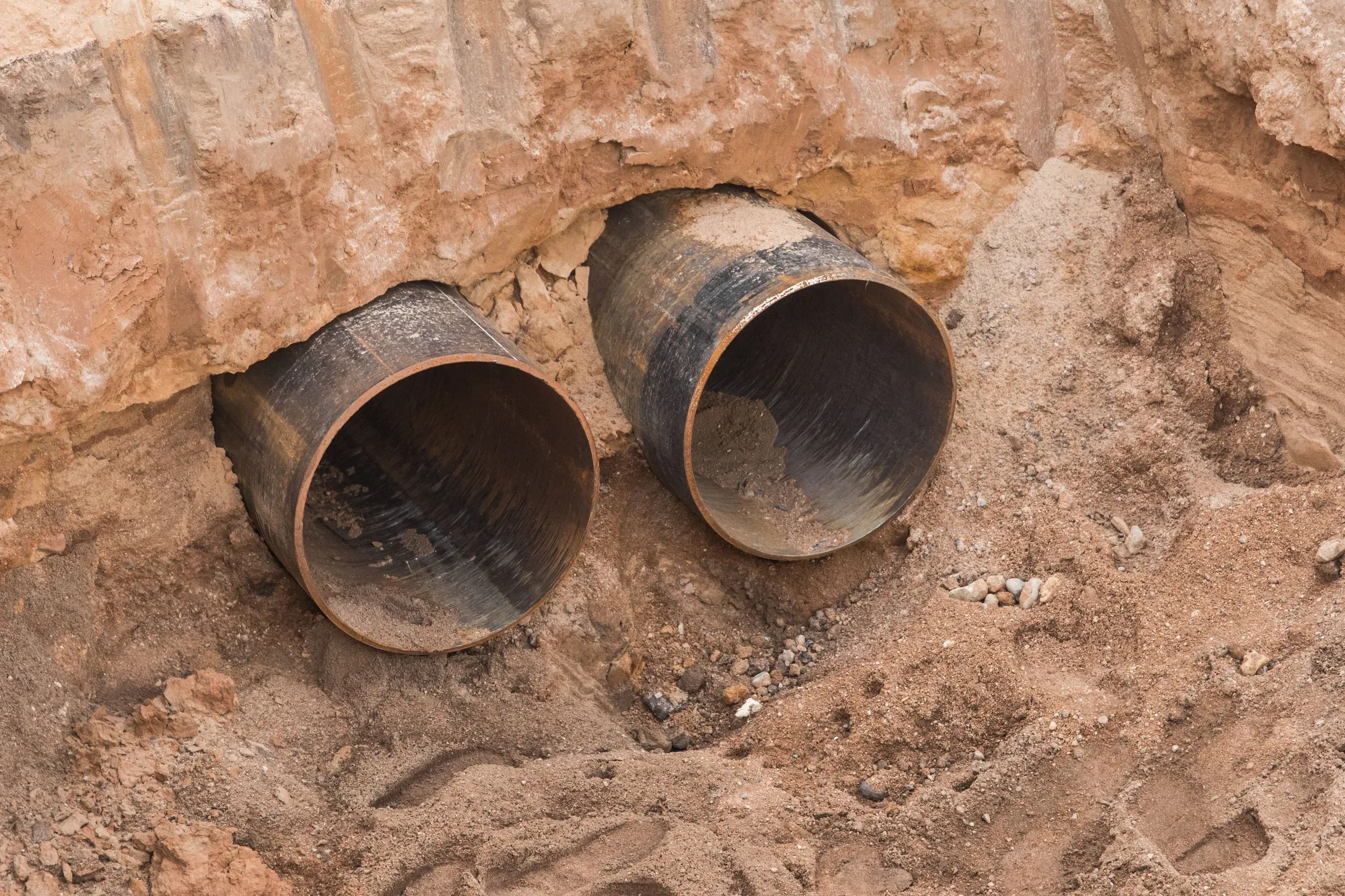 Coated steel pipe ends exposed in an excavated trench