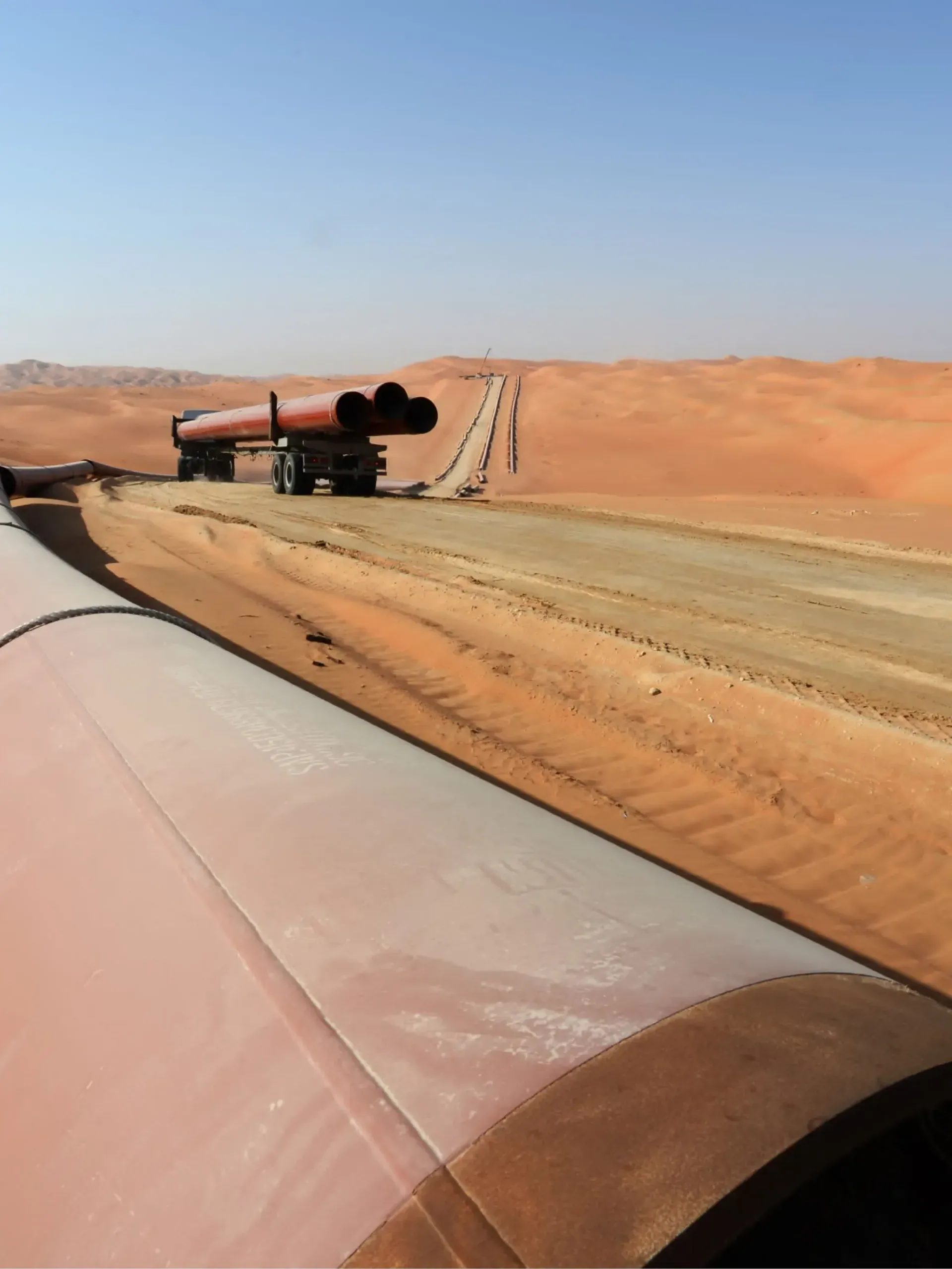 Pipeline under construction across desert dunes