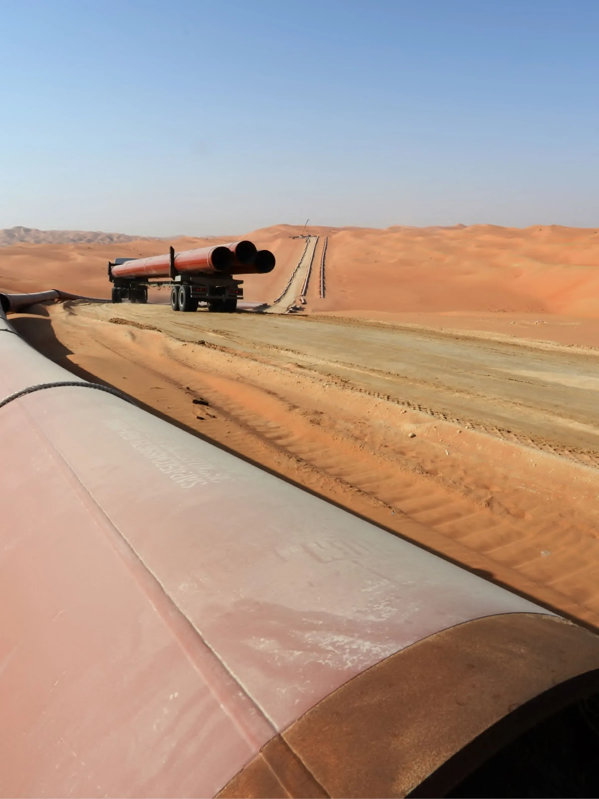 Pipeline under construction across desert dunes