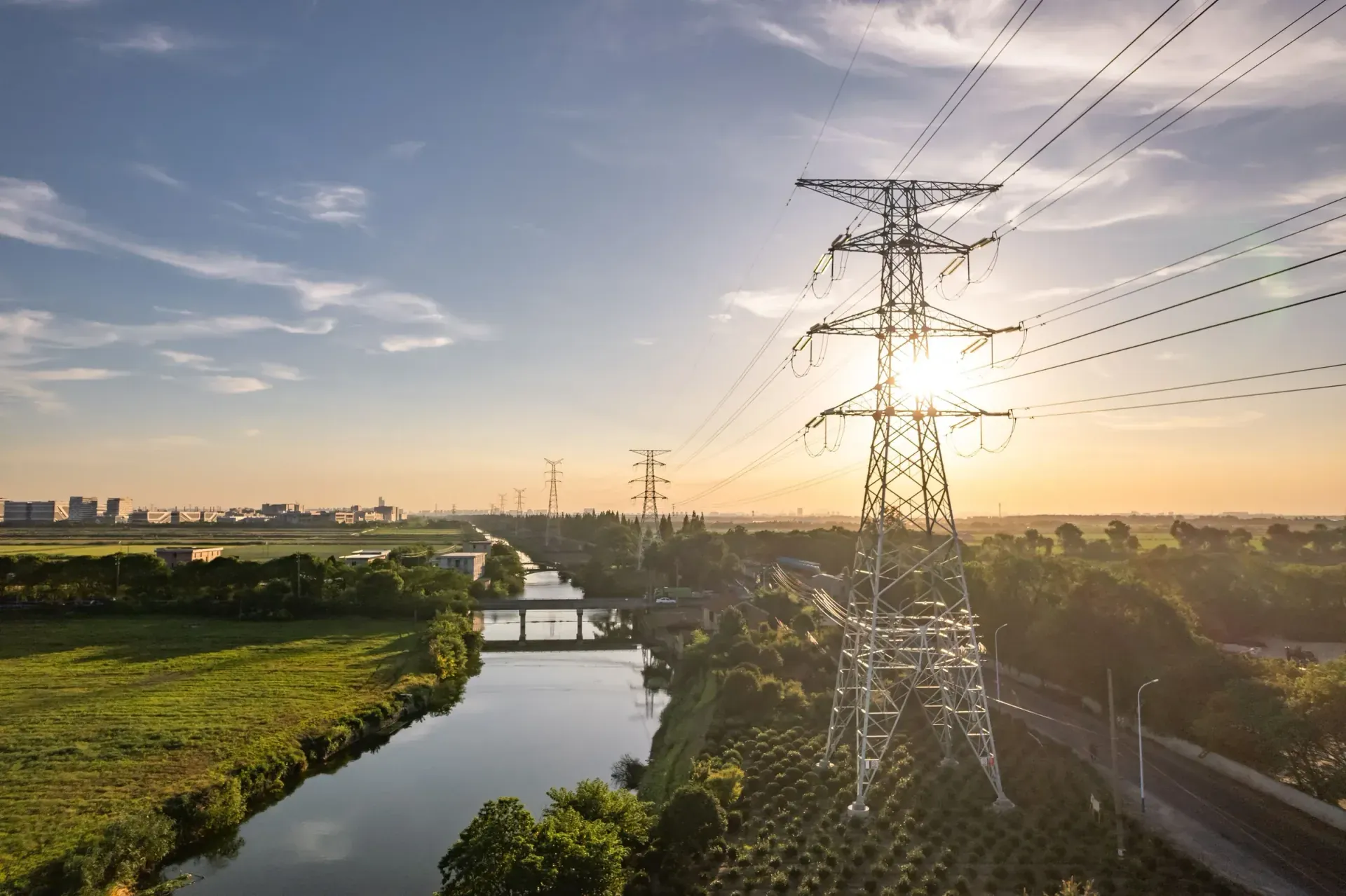 High-voltage transmission line crossing farmland at sunset