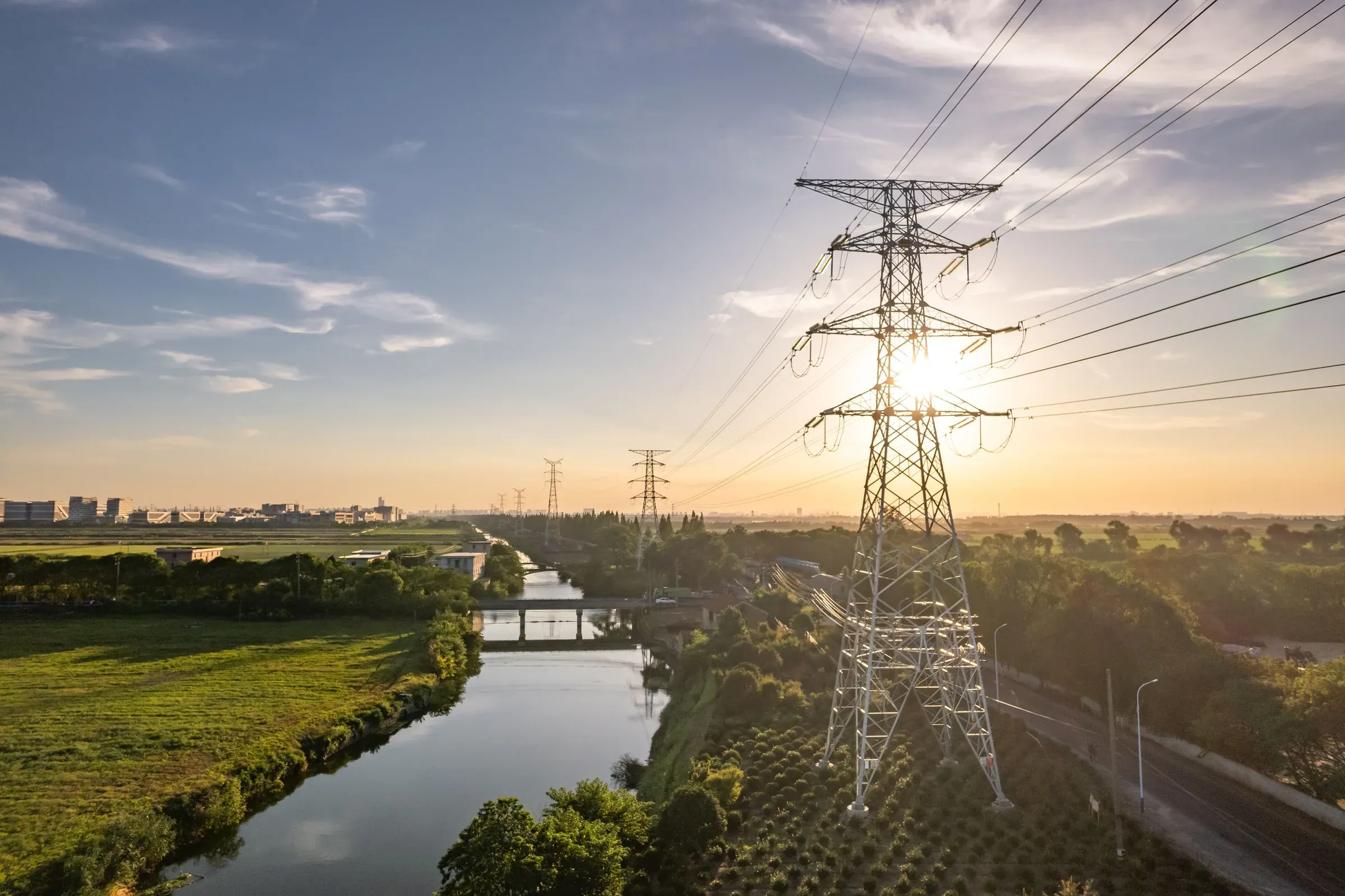 High-voltage transmission line crossing farmland at sunset