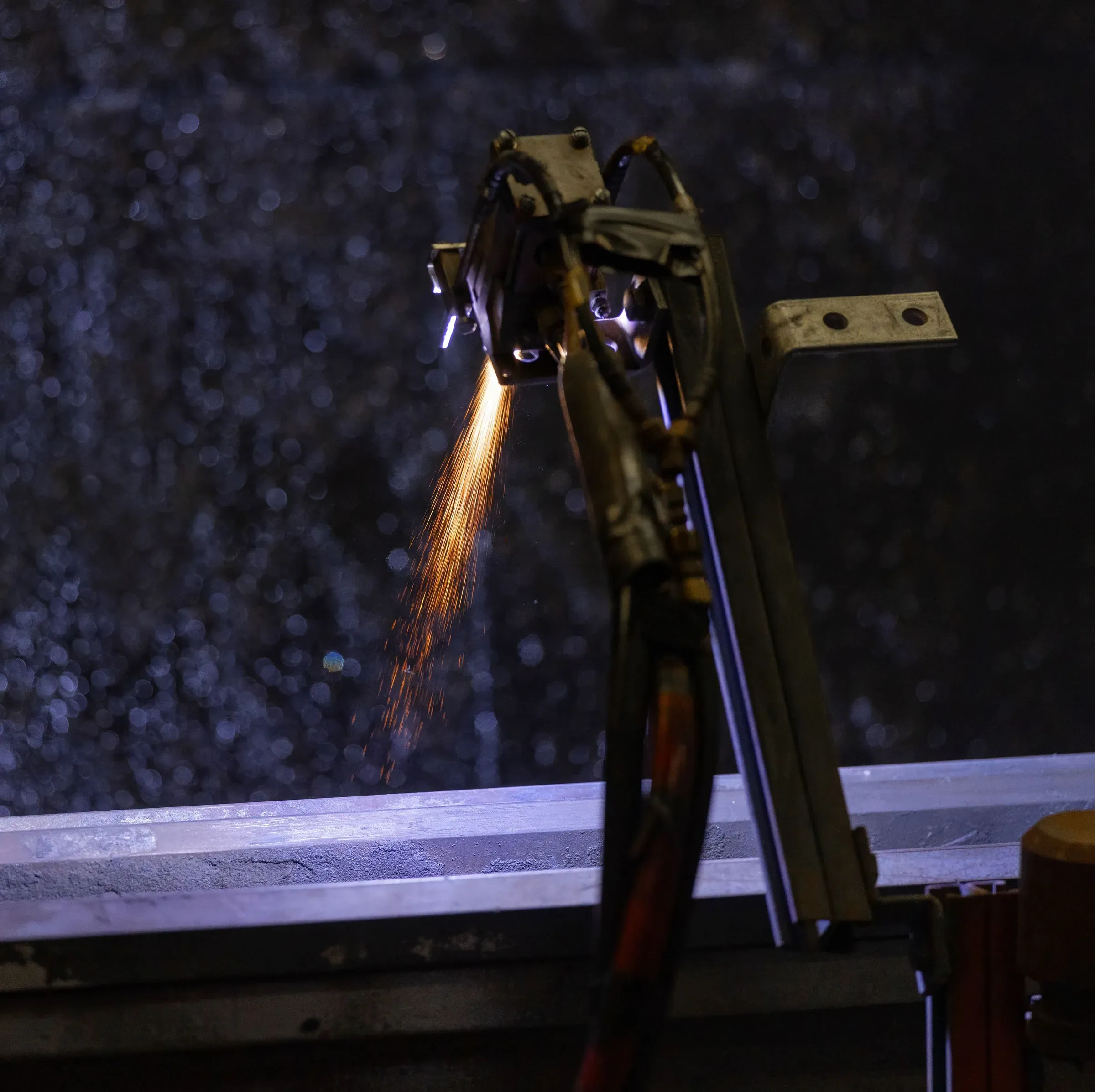 Thermal spray plume against a dark spray booth interior