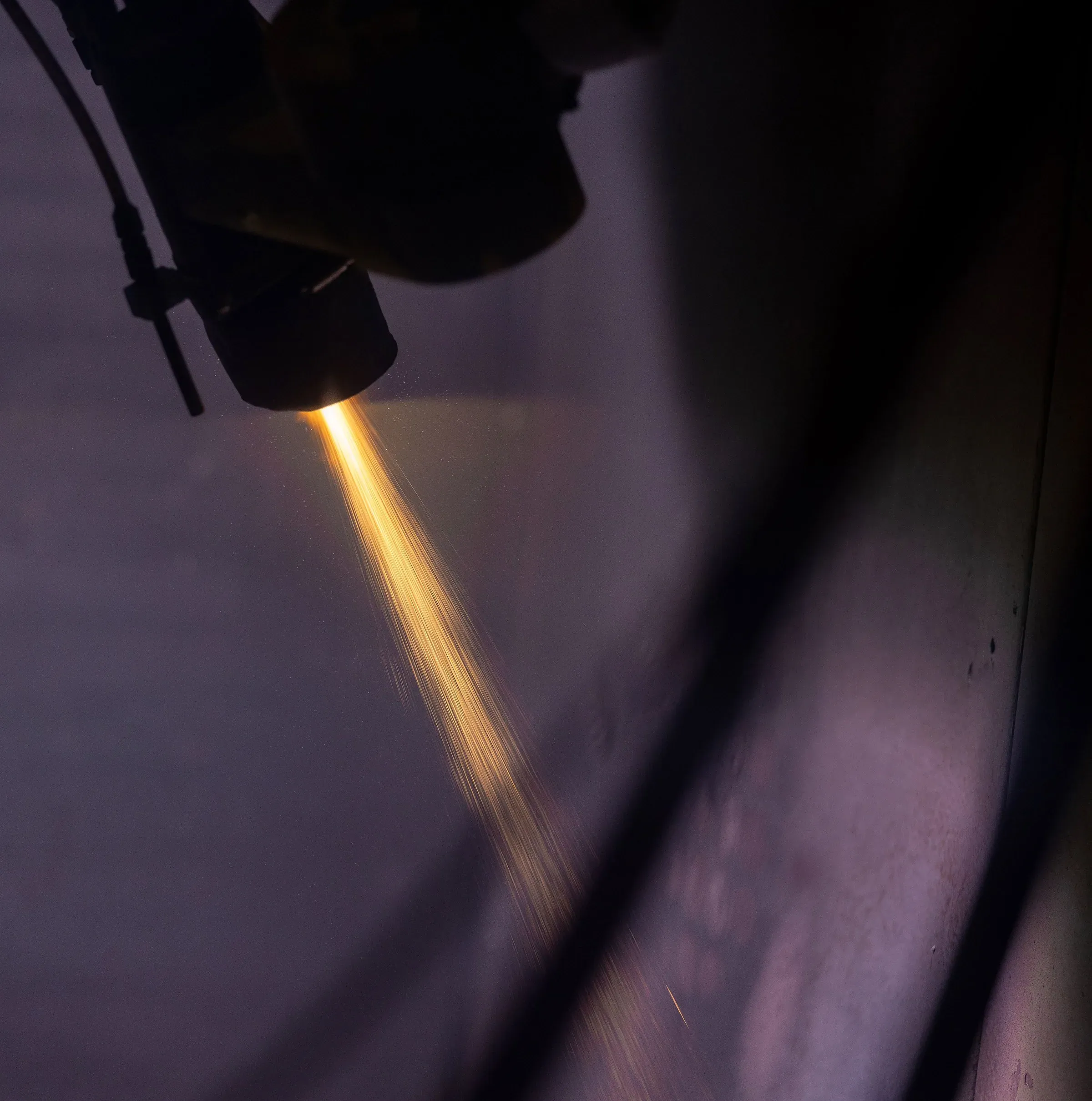 Plasma spray gun laying a molten coating stream onto a rotating component
